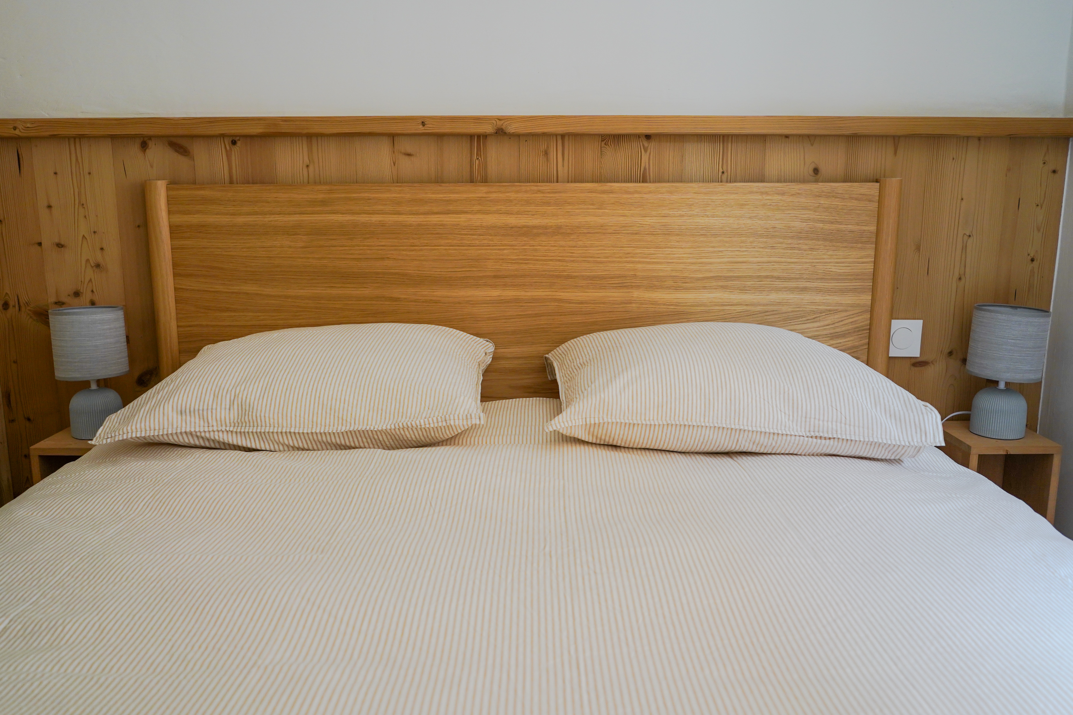 Chambre principale avec tête de lit en chêne et bardage bois